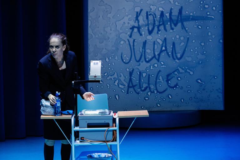 Skådespelare vid overheadapparat med text projekterad bakom.