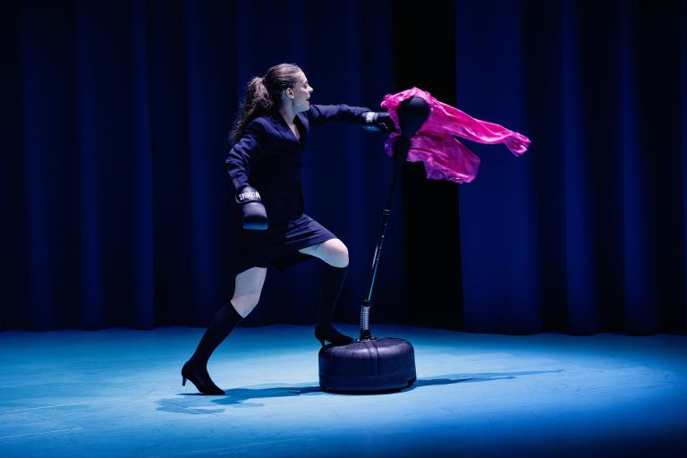 Skådespelare slår på boxningsdocka med rosa tyg.