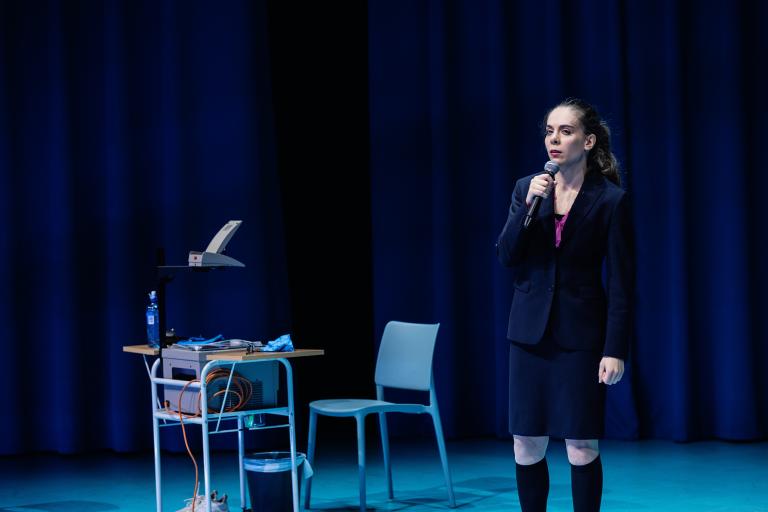 Skådespelare håller mikrofon på scen.