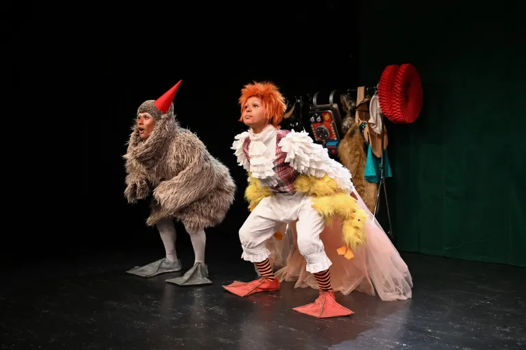 Två skådespelare i djurkostymer hukar bredvid varandra på scenen.