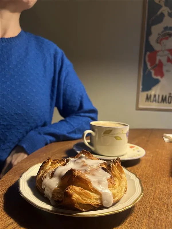 Winerbröd, en kopp kaffe, person i blå tröja