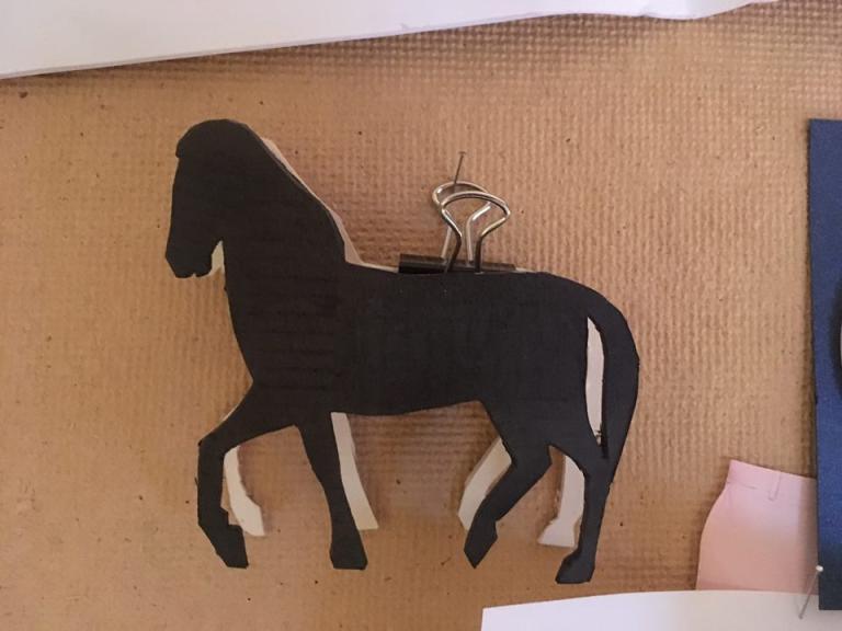 En häst i svart papper hänger på en anslagstavla