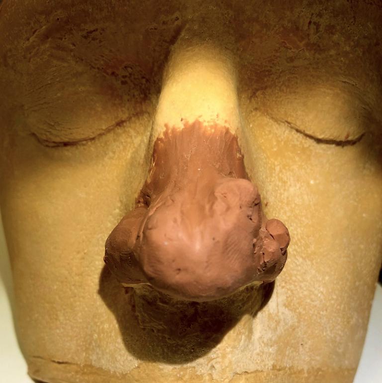 Närbild av leraa som formar en stor näsa på gispavgjutningen