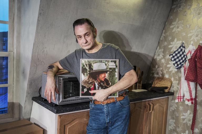 Konrad står i köket lutad över mikrovågsugnen och håller i sitt favoritalbum Desire