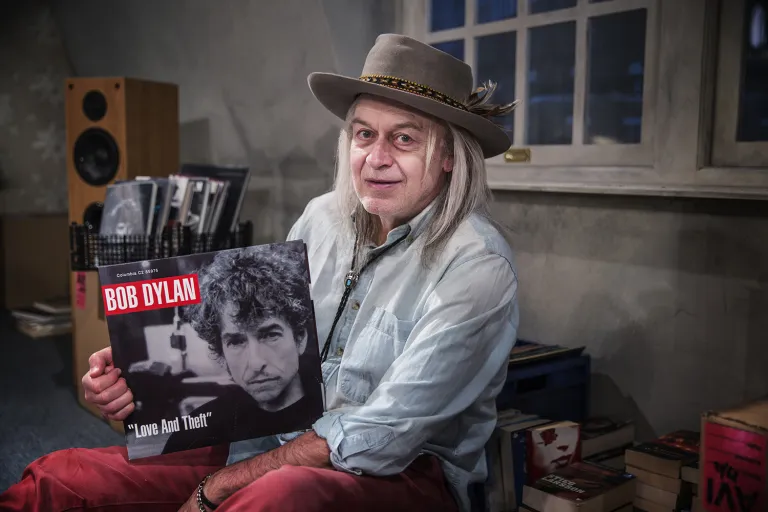 Bror sitter på golvet bredvid en back med skivor och håller upp sitt favoritalbum Love and theft