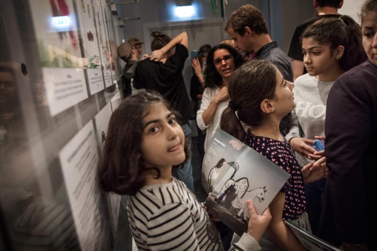 Flicka står bland publiken i foajén och tittar i ett föreställningsprogram