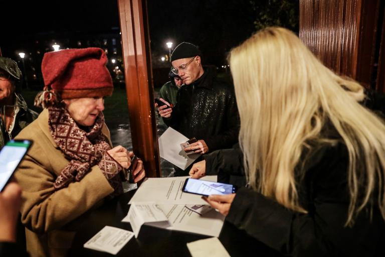 Kvinna står i entrén till teatern och tar fram sin legitimation. Teaterns medarbetare tittar på ett papper som kvinnan lämnat på bordet mellan dem.