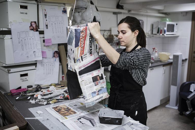 Kroppen till en docka hänger på en galge och kläs in med tidningspapper