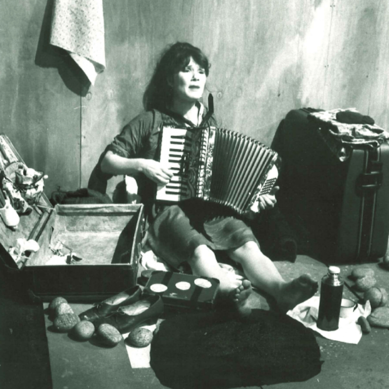 Kvinna sitter på golvet i ett rum och spelar dragspel 