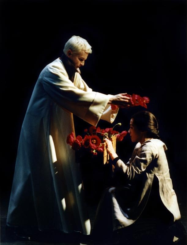 En person sätter en röd blomsterkrans på en annan persons huvud