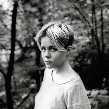 Mare Kandre tittar upp mot kameran. Svartvit bild med skog i bakgrunden.