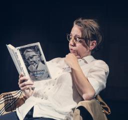 Kvinna sitter ner i en stol och läser en bok om Barbro Alving.