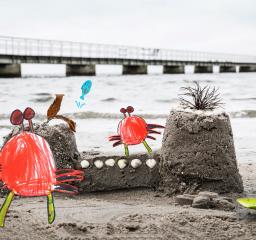 Ritade krabbor på en riktig sandstrand vid ett sandslott