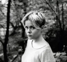 Mare Kandre tittar upp mot kameran. Svartvit bild med skog i bakgrunden.