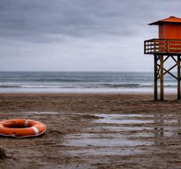 Bild på öde strand med en livboj och badvaktstorn