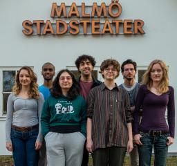 Gruppbild med sju ungdomar står framför en Malmö Stadsteaterskylt i utomhusmiljö