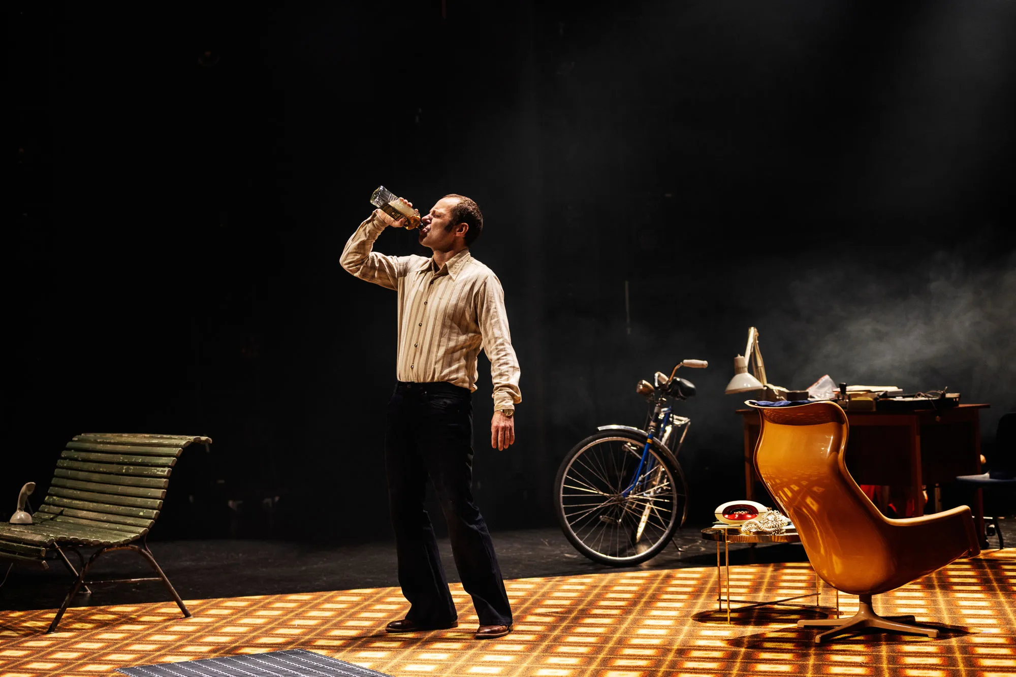 En man på scenen ensam. Halsar en dryck ur en flaska.