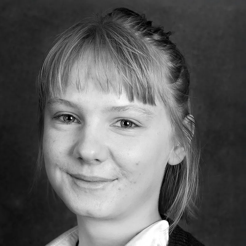 Porträttbild svartvit. Person med lugg, hår uppsatt och vit blus. 