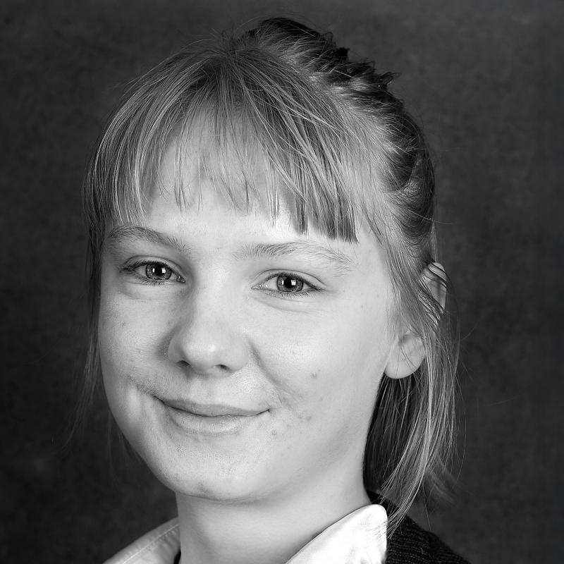 Porträttbild svartvit. Person med lugg, hår uppsatt och vit blus. 