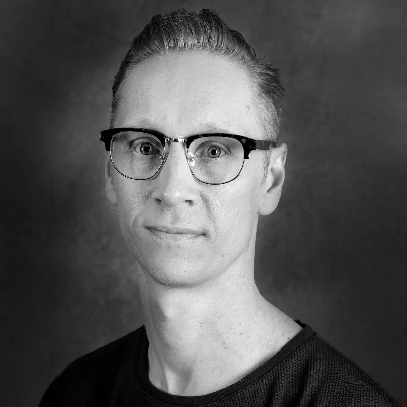 Porträttbild svartvit. Person med bakslickat hår och svart tshirt