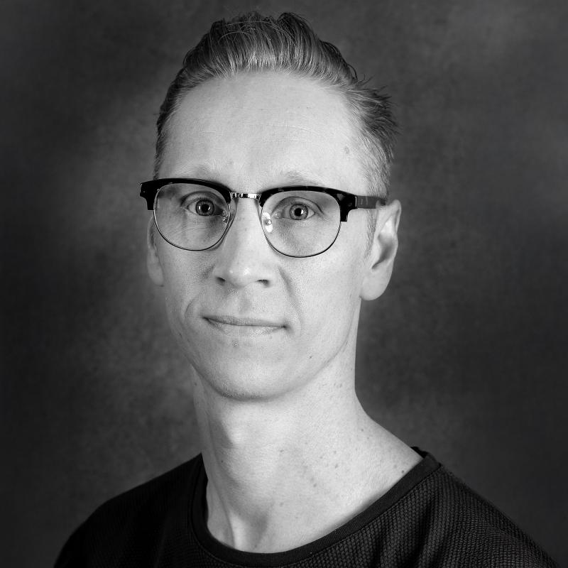 Porträttbild svartvit. Person med bakslickat hår och svart tshirt