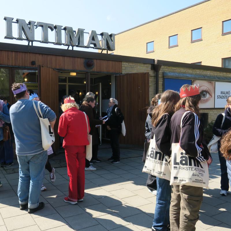 unga personer står utanför en ingång med skylt "intiman". Några bär pappkronor på huvudet och tygpåsar där det står "länk" på.