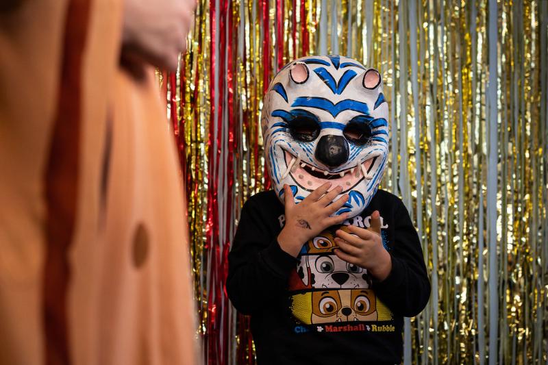 En person med monstermask står framför ett draperi i guld