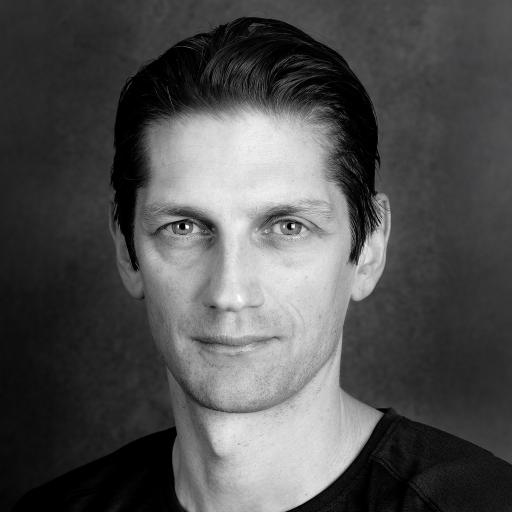 Porträttbild svartvit. Person med bakslickat hår och svart tshirt