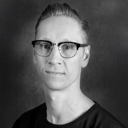 Porträttbild svartvit. Person med bakslickat hår och svart tshirt