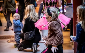 barn som dansar hoppsasteg, ballerina i bakgrunden tillsammans med andra familjer