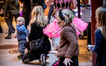 barn som dansar hoppsasteg, ballerina i bakgrunden tillsammans med andra familjer