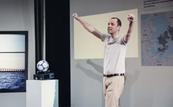 Man står med armarna i segergest och en fotboll ligger ovanpå en diaprojektor i bakgrunden