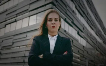 Kvinna med korslagda armar framför ett hus