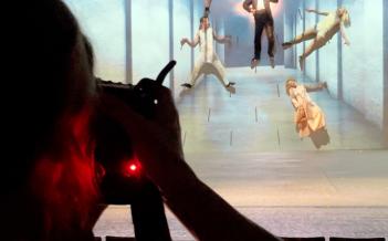 Foto: Erik Roman Föreställningsfotografen Emmalisa Pauly syns i förgrunden med kameran riktad mot scenen under fotografering av Ett drömspel på Hippodromen 2024. På scenen hänger och flyger skådespelare och cirkusartister i en blåskimrande, drömlik miljö.