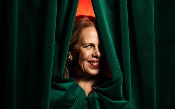 Porträtt på Petra Brylander. Kikar fram bakom en grön ridå.