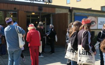 unga personer står utanför en ingång med skylt "intiman". Några bär pappkronor på huvudet och tygpåsar där det står "länk" på.