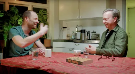 Två män pratar sittandes vid ett köksbord